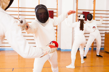 Athletes at fencing workout, practicing attack movements in duel