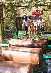 Two teams compete on an obstacle course in an amusement park.