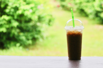 Cold coffee is placed on a wooden table in the midst of nature.