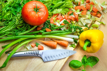 Mixed vegetables with a knife on a chopping board including tomato pepper and parsley ready for making a stew.