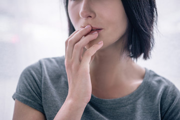 Cropped view of lonely woman covering mouth at home