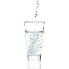 Water pouring into glass on white background