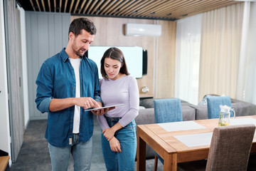 Young man explaining his wife how to use new smart remote control application