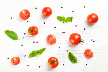 Bunch of juicy organic red cherry tomatoes arranged with green basil leaves on isolated white background. Polished vegetables. Clean eating concept. Vegetarian diet. Copy space, flat lay, top view.