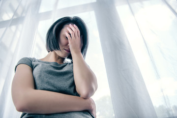 low angle view of depressed woman covering face at home