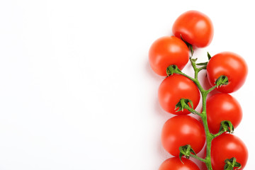 Branch of juicy organic red cherry tomatoes arranged in row on isolated white background. Polished vegetables. Clean eating concept. Vegetarian diet. Copy space, flat lay, top view.