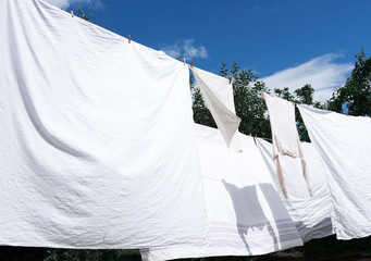 Snow-white clean sheets hang on a rope and dry outdoors