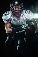 American football sportsman player in helmet on black background with smoke. Sport and motivation wallpaper.