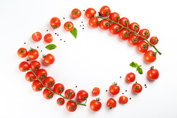 Bunch of juicy organic red cherry tomatoes arranged with green basil leaves on isolated white background. Polished vegetables. Clean eating concept. Vegetarian diet. Copy space, flat lay, top view.