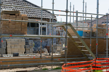 Renovation projects. Building of extension of the existing house, unfinished brick walls, block work, insulation, stacks of materials on scaffoliding, selective focus