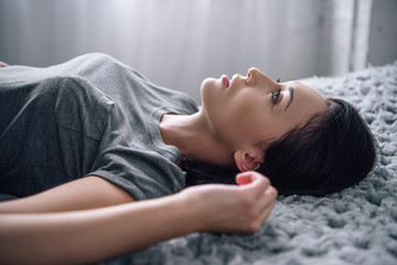 beautiful depressed woman lying on bed at home