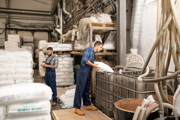 Young workers of large factory scattering polymer grains into huge container