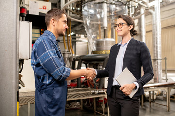 Young female partner shaking hand of engineer of chemical processing factory