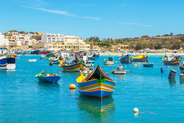 Fototapeta na wymiar The traditional eyed boats in the harbor of fishing village Marsaxlokk in Malta