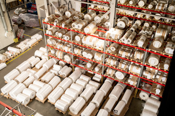 Many rolled polyethylene film units on shelves and racks inside warehouse