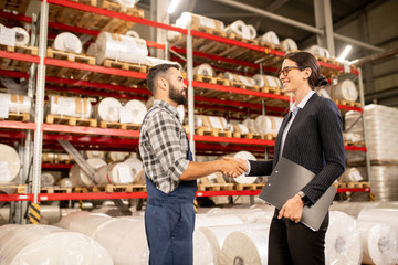 Successful partners handshaking in warehouse of large factory after negotiation