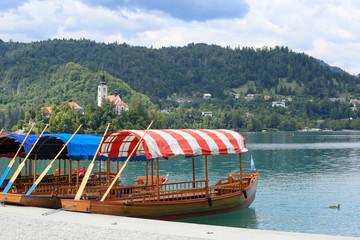 Lake Bled with traditional boats. Beautiful mountain lake in summer with small Church on island...
