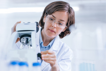 Woman does scientific research with the microscope in the lab.