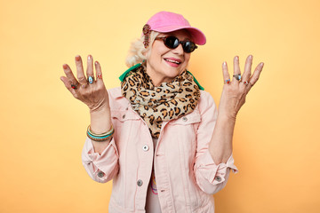 stylish happy cheerful woman in sunglasses with raised hands, showing her rings on fingers ,looking at camera. high fashion, style