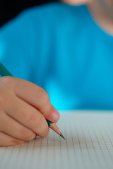 Pencil in a child's hand on a blank sheet of paper