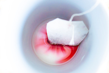 A tea bag creating colorful patterns in a mug