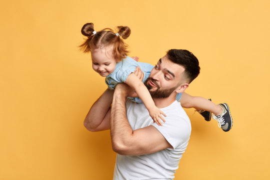 caring father holding, lifting his adorable child on yellow background. close up photo. funny time with dad. I love you. my daddy