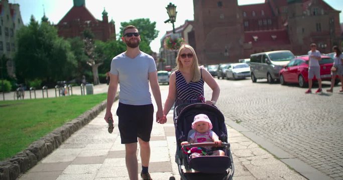 Young couple walk with stroller on the street