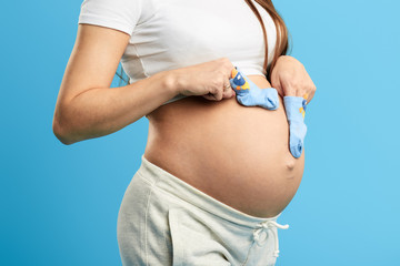 pregnant girl has put on socks on her fingers,she is touching her belly, sensitivity concept. close...