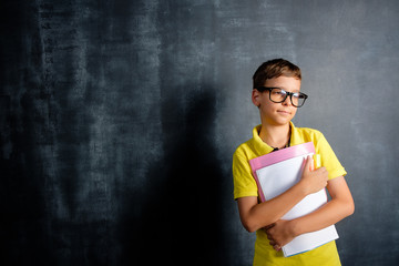 Schoolboy on the background of a blackboard with divorces from chalk. Back to school concept with copy space.