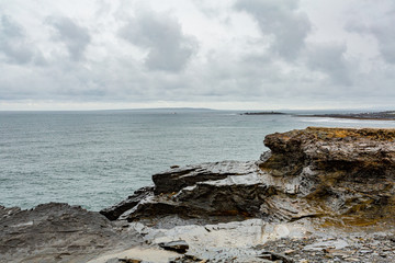 Limestone rocks and the sea along the coastal walk route from Doolin to the Cliffs of Moher, geosites and geopark, Wild Atlantic Way, rainy day in county Clare in Ireland