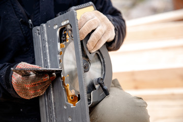 Builder grinds iron teeth using portable circular saw tool to cut wood