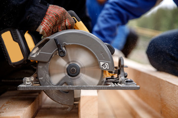 Builder uses portable circular saw tool to cut wood