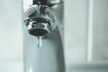 water drop dripping from the tap and water shortage