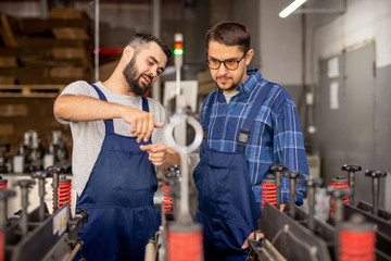 Young engineer explaining his trainee how to serve and use technical equipment