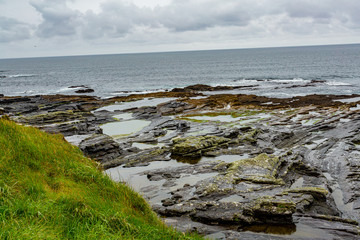 Fototapeta na wymiar Irish limestone landscape on the coast in the coastal walk route from Doolin to the Cliffs of Moher, geosites and geopark, Wild Atlantic Way, rainy day in county Clare in Ireland