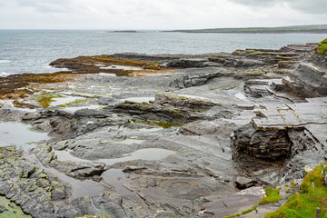 Limestone landscape on the coast in the coastal walk route from Doolin to the Cliffs of Moher, geosites and geopark, Wild Atlantic Way, rainy day in county Clare in Ireland