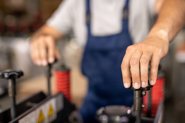 Hand of technician or engineer turning one of handles of industrial equipment