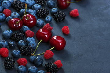 Blackberries,blueberries,raspberries,cherries on black concrete background. Healthy food