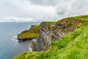 Beautiful view of the sea and the limestone rock cliffs along the coastal walk route from Doolin to the Cliffs of Moher, geosites and geopark, Wild Atlantic Way, spring day in county Clare in Ireland