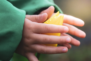 Close-up image of the hands of a little girl trying to touch a yellow tulip flower