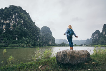 Naklejka na ściany i meble Caucasian blonde woman overlooking limestone mountains in Ninh Binh province, Vietnam