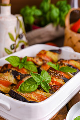 Traditional italian food. Eggplant and tomatoes with parmesan. Baked summer wax with sauce, cheese and basil. Healthy lunch for the family.