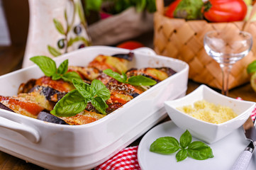 Traditional italian food. Eggplant and tomatoes with parmesan. Baked summer wax with sauce, cheese and basil. Healthy lunch for the family.