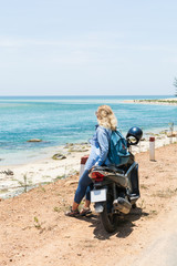 Obraz na płótnie Canvas Woman riding motorcycle along the sea on the road to Hai Van pass, Vietnam