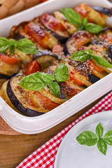 Traditional italian food. Eggplant and tomatoes with parmesan. Baked summer wax with sauce, cheese and basil. Healthy lunch for the family.