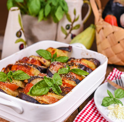 Traditional italian food. Eggplant and tomatoes with parmesan. Baked summer wax with sauce, cheese and basil. Healthy lunch for the family.