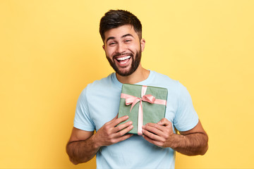 handsome bearded overjoyed man wearing casual clothes holding present box standing isolated over yellow background,Birthday party. celebration, happiness, best present from girlfriend - 282323731