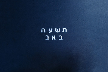 School black chalkboard with text Tisha B'Av written in hebrew. Tisha B'Av day in Judaism, on which a number of disasters in Jewish history occurred.