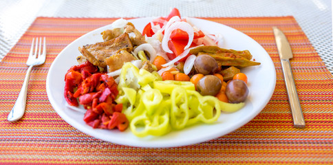 Healthy food, plate full with meat and vegetables, olives, paprika, tomatoes, baby carrots and onions