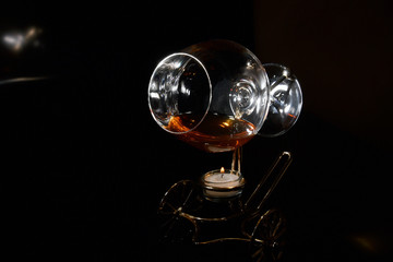 A glass of cognac on a special stand with candle for warming drink in the dark